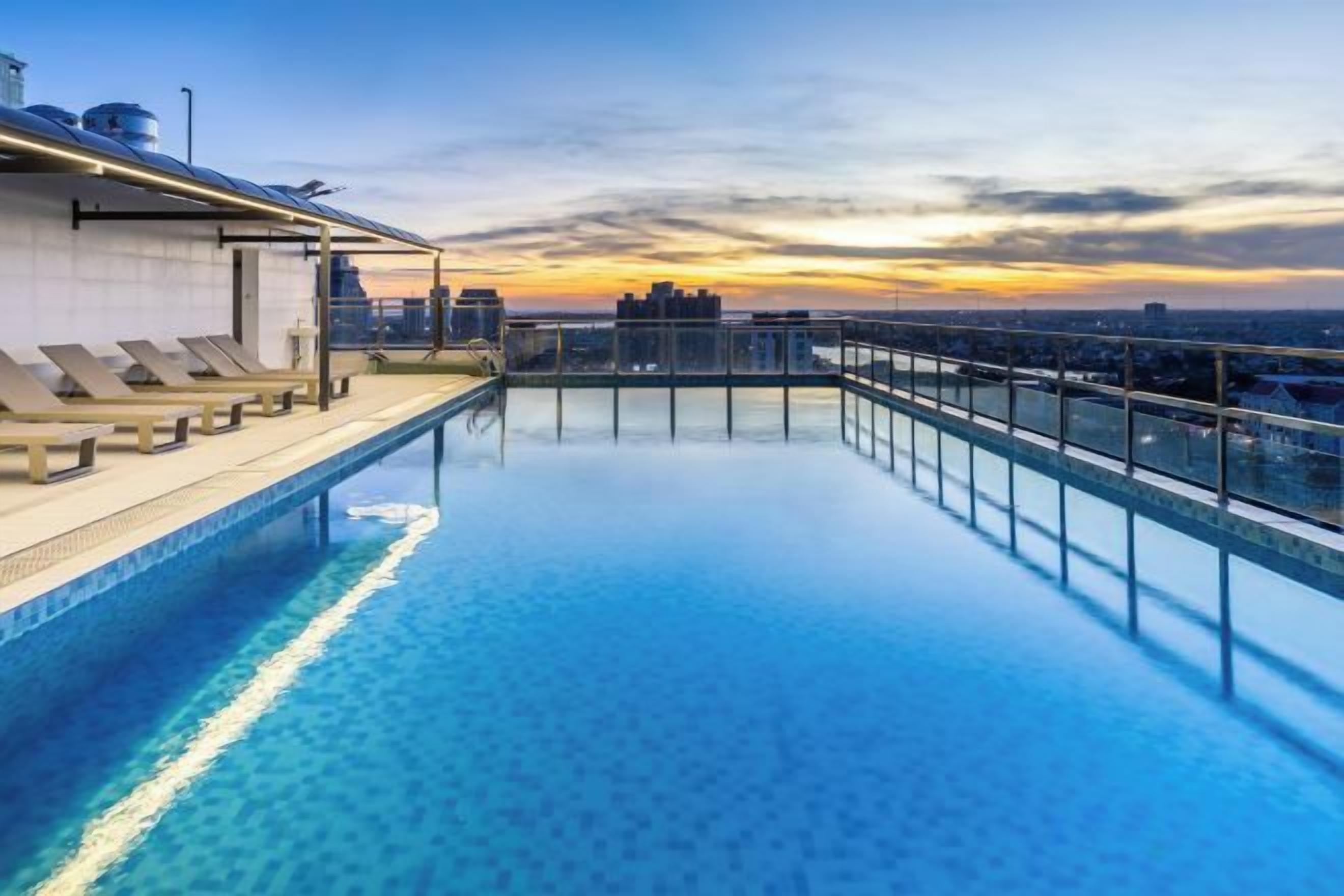 A rooftop infinity pool with a city view at sunset.