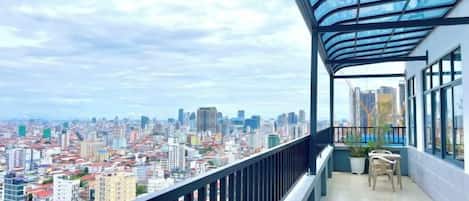 A balcony with a city view, a table, and a chair.