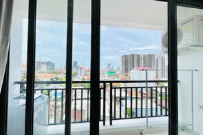 Un balcón con vista a la ciudad, un aire acondicionado Samsung y una puerta de cristal.