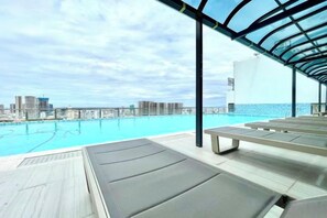 Ein Pool auf dem Dach mit Liegestühlen und Blick auf die Stadt.