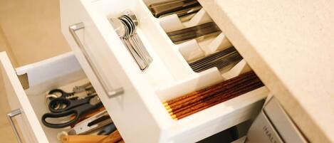 A drawer with various kitchen utensils, including scissors, a whisk, and wooden spoons.