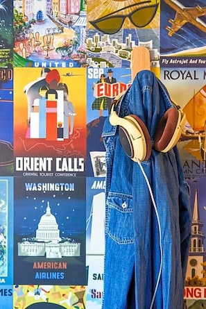 A person wearing headphones with a denim jacket, standing in front of a wall with various travel posters. - Hotelf1 Mulhouse Centre Ouest (Mulhouse)