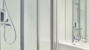 A modern bathroom with a glass shower enclosure, a white sink, and a mirror.