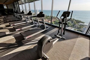 A gym with treadmills and exercise equipment, large windows with a view of the sea. - Andromeda Condominium Seaview Amazing Room (Pattaya)