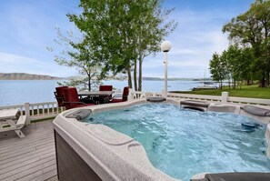 Un bain à remous avec une terrasse en bois, du mobilier d’extérieur et une vue sur un lac.