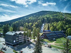 Un bâtiment moderne doté d’un parking, d’un télésiège et surplombant un paysage montagneux.