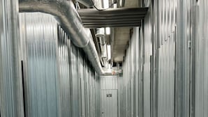 A corridor lined with metal lockers, a tiled floor, and visible ductwork on the ceiling.