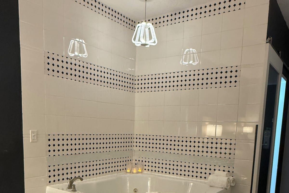 Une salle de bain moderne avec une baignoire sur pieds, des carreaux de sol à motifs hexagonaux et un motif géométrique sur le mur.