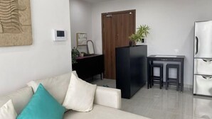 Ένα σύγχρονο σαλόνι με έναν καναπέ, ένα μικρό τραπέζι και ένα ψυγείο.