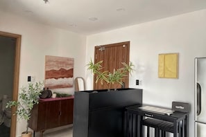 A modern kitchen with a black countertop, wooden cabinet, and a refrigerator. - Happy One Central - Apartment Thu Dau Mot (Thu Dau Mot)