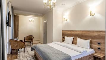 Ett hotellrum med en stor säng, ett träbeklätt sänggavel, sängbord, en stol och ett skrivbord.