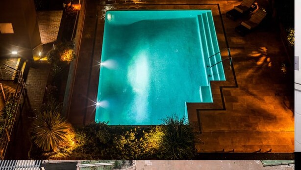 Une piscine rectangulaire avec des marches permettant d’y accéder, entourée d’une terrasse en bois et de quelques plantes.
