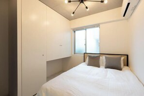 A bedroom with a bed, a window, and built-in wardrobes. - LUXE Minami Aoyama (Tokyo)