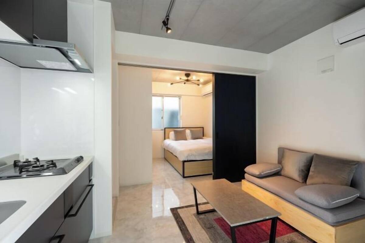 A compact living space with a kitchenette, a bed, a sofa, and a small table.