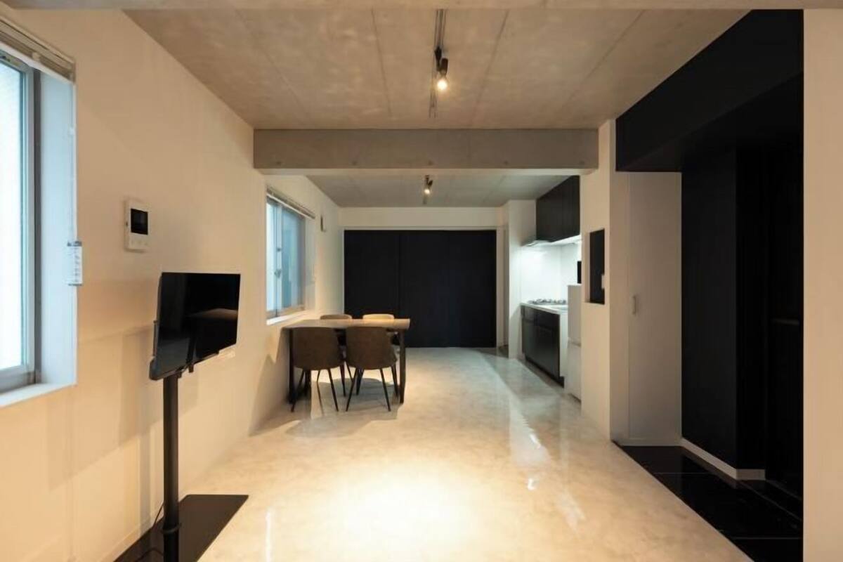 A hallway with a dining area, a TV, and a kitchen area.