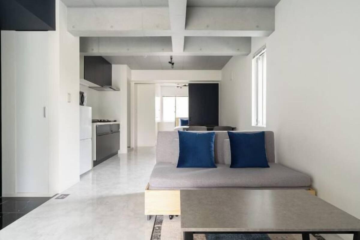 A modern living space with a sofa, a dining table, and a kitchen area.