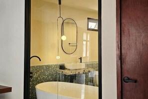 A bathroom with a freestanding bathtub, a mirror, and a towel rack. - Yaowarat Stay (Bangkok)
