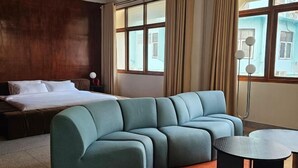 A modern hotel room with a large bed, a teal sofa, and a small table. - Yaowarat Stay (Bangkok)