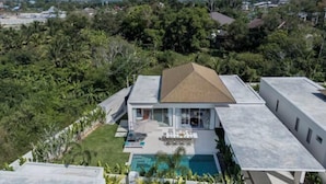 A modern house with a swimming pool, surrounded by lush greenery and mountains in the background. - Two Flamingo Villa 2 (Phuket)