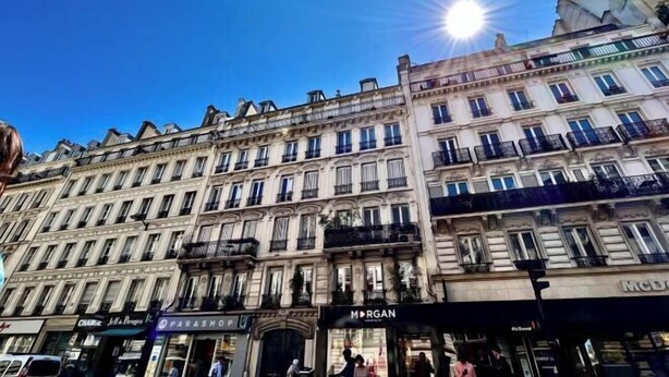 Un immeuble à plusieurs étages, avec différentes boutiques en rez-de-chaussée, dont un McDonald's bien visible.