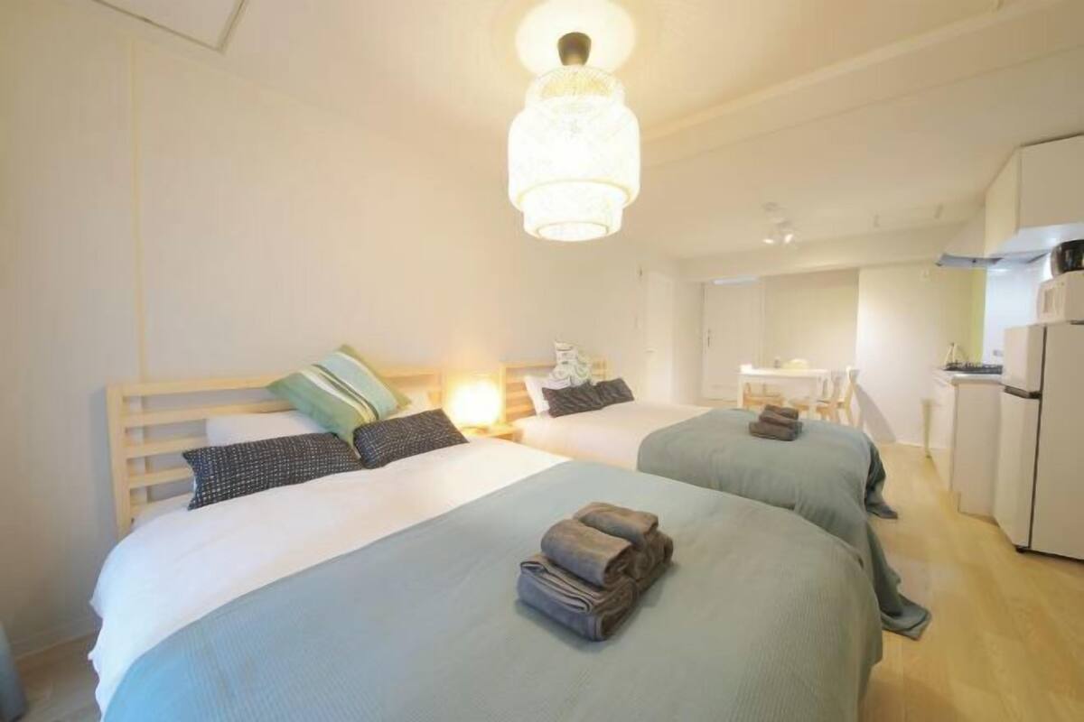 A hotel room with two beds, a kitchenette, and a dining area.