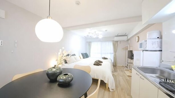 A modern kitchen with a dining table, a refrigerator, and a sink. - Mansion Cattleya. (Sapporo)