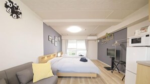 A modern room with a bed, a sofa, a TV, and a kitchenette. - Mansion Cattleya. (Sapporo)