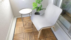 A corner room with a white chair, a small round table, and a potted plant. - Mansion Cattleya. (Sapporo)