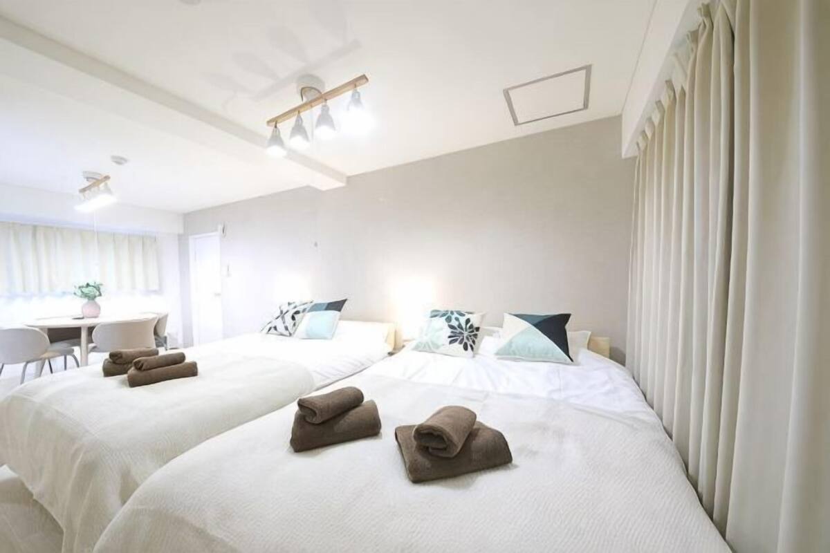 A hotel room with two beds, a desk, and a chair.