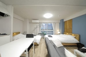 A hotel room with two beds, a desk, a chair, a laptop, and a window with curtains.