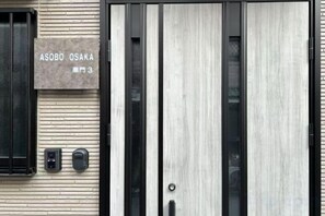 A building entrance with a sign reading 'ASOBO OSAKA' and a door with a vertical panel design. - ASOBO OSAKA Kuromon 3rd (Osaka)