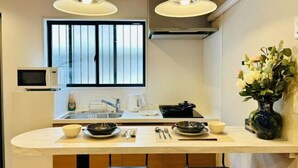 A compact kitchen with a microwave, sink, and dining area. - ASOBO OSAKA Kuromon 3rd (Osaka)