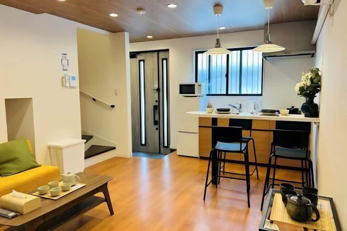 A modern living room with a sofa, coffee table, and a kitchen area with a dining table and chairs.