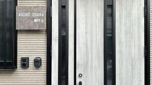 A building facade with a sign reading "ASOBO OSAKA" and a door with a vertical wooden panel design. - ASOBO OSAKA Kuromon 3rd (Osaka)