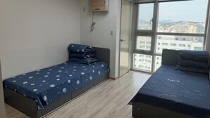 A bedroom with a bed, a desk, and a window with a city view. - HaiLun Officetel (Seoul)