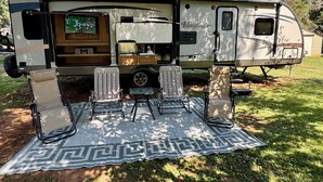 A recreational vehicle with a kitchen area, a television, and a dining setup with chairs and a table. - Cozy RV in quaint Nicholson. Close to UGA. (Nicholson)