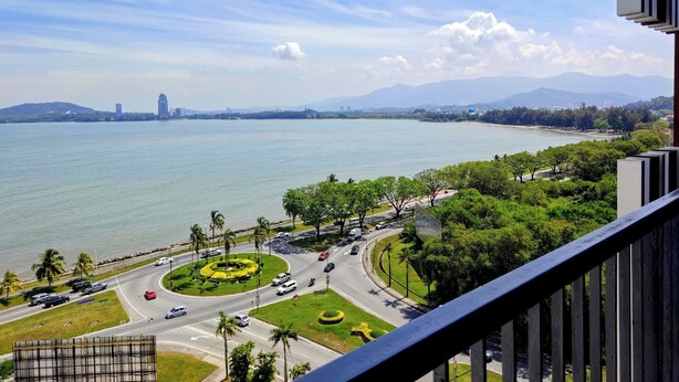 A view of a coastal city with a roundabout, palm trees, and a body of water. - Bay Win La.mer Butik (Kota Kinabalu)