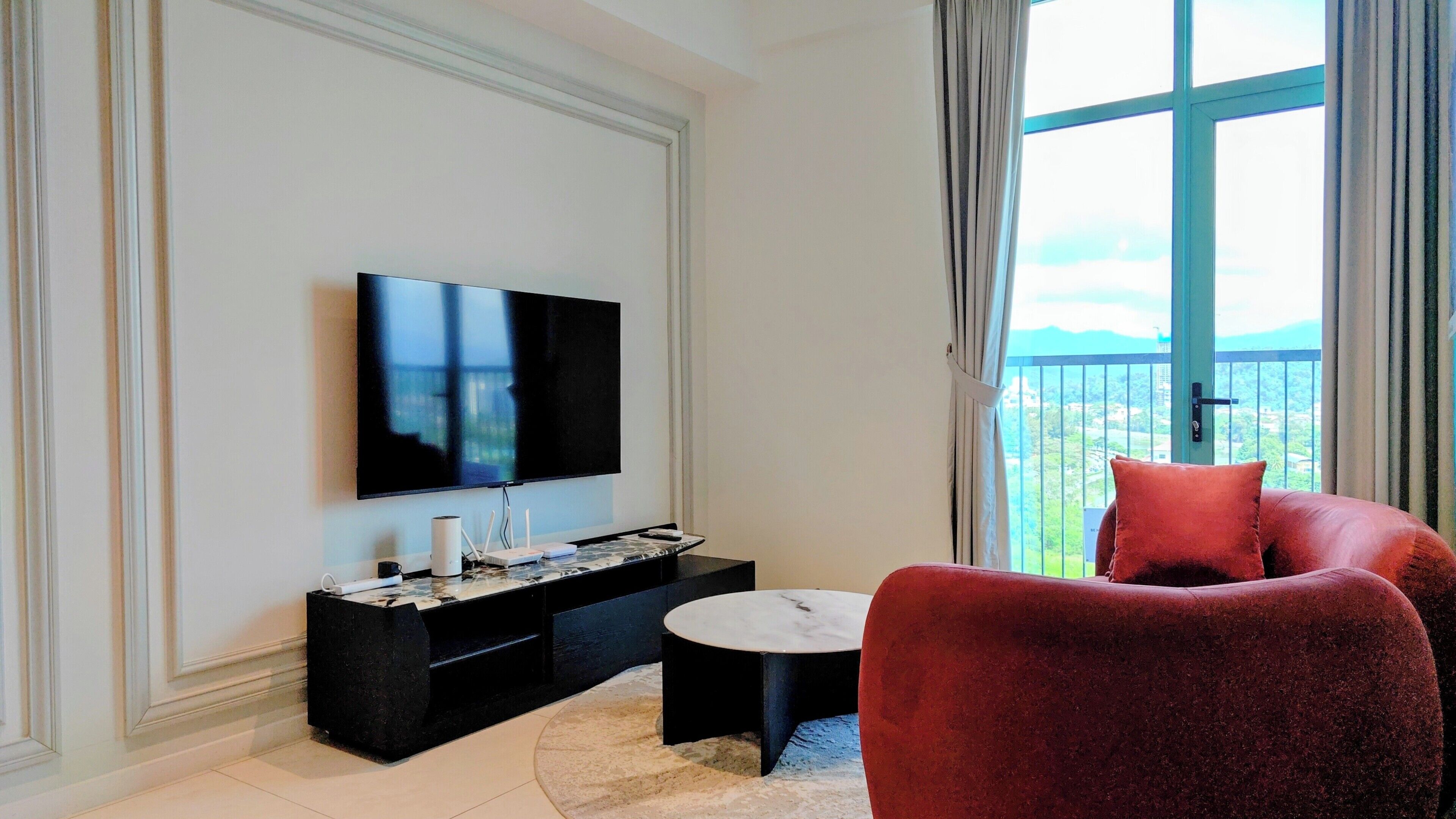 Una sala de estar moderna con un televisor de pantalla plana, un mueble de entretenimiento negro, una mesa de centro redonda y un sofá rojo.