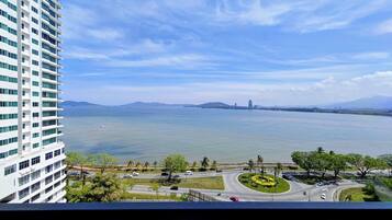 A high-rise building with a view of a large body of water, a roundabout, and distant mountains.