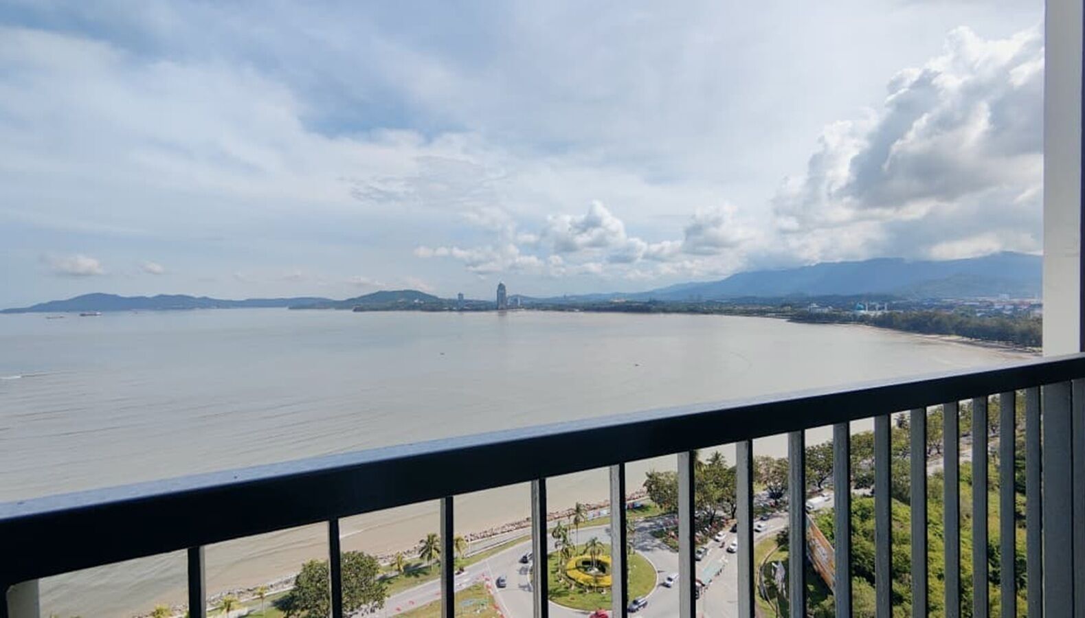 Uitzicht vanaf een balkon over een groot wateroppervlak, met verre landschappen en een brug.
