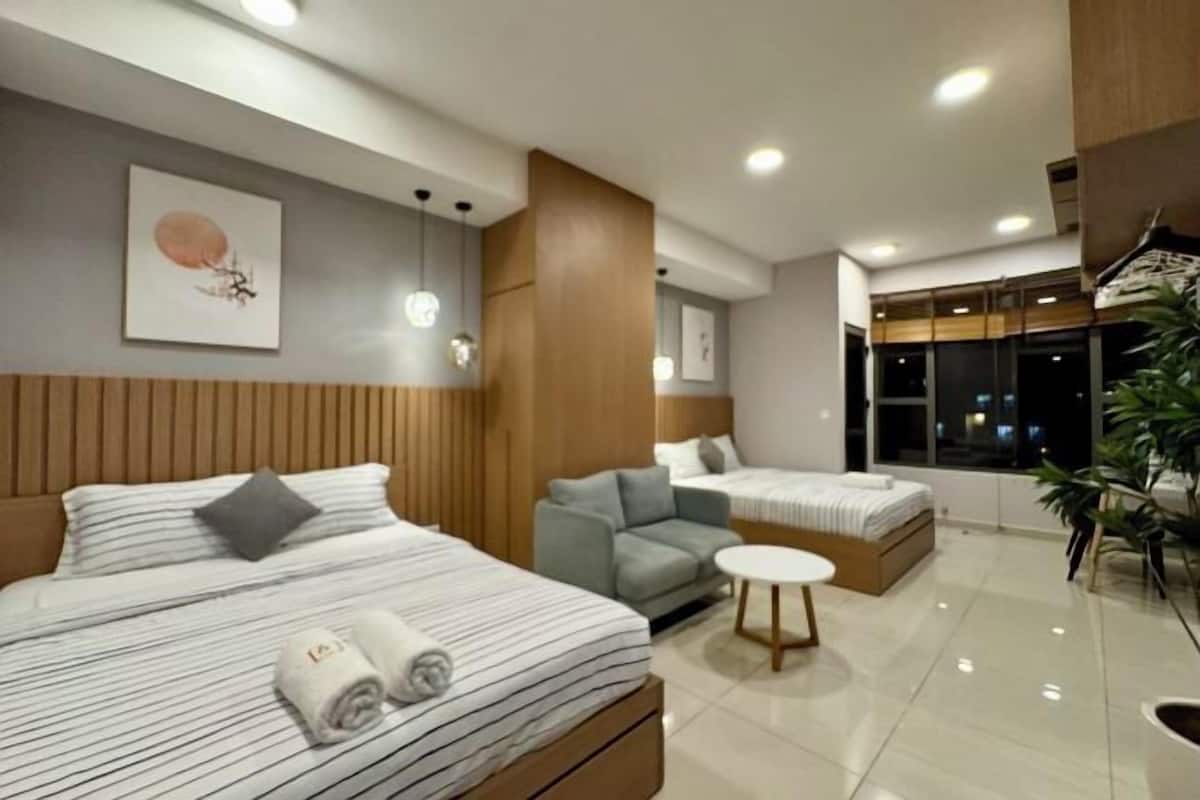 Ein modernes Hotelzimmer mit Bett, Sofa, kleinem runden Tisch und einem großen Fenster.