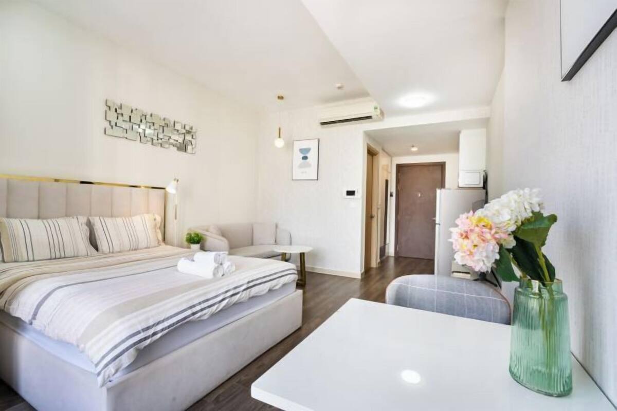 Ein modernes Hotelzimmer mit Bett, Nachttisch und einer Blumenvase.