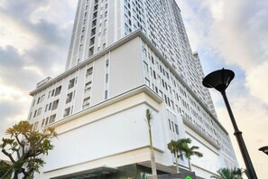 A tall white building with a modern design, featuring a prominent entrance and a street lamp nearby. - MIN' Apartment - Rivergate Residence Downtown BUI VIEN - FREE POOL (Ho Chi Minh City)