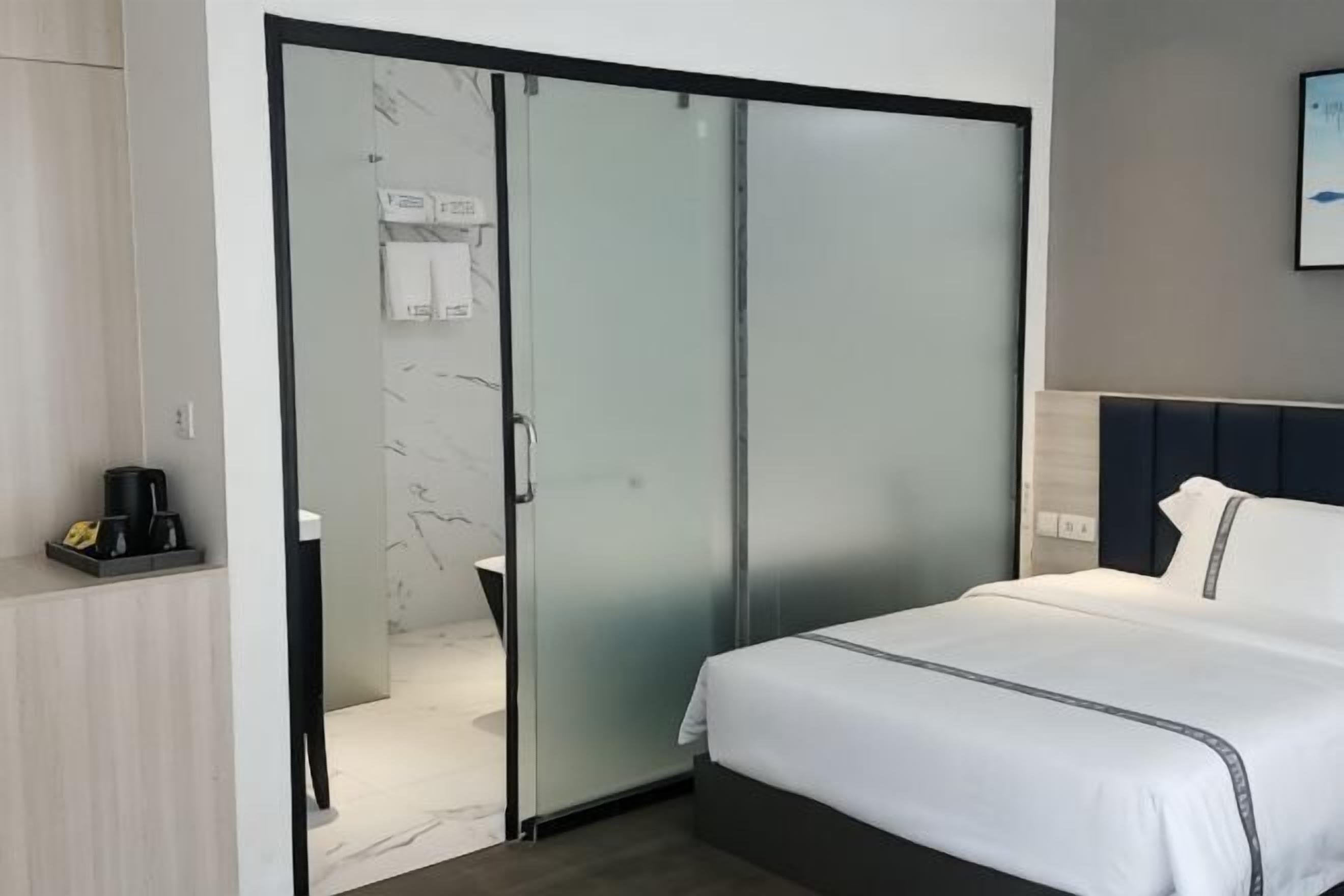 A hotel room with a bed, a sliding door closet, a coffee maker, and a bathroom visible through the door.
