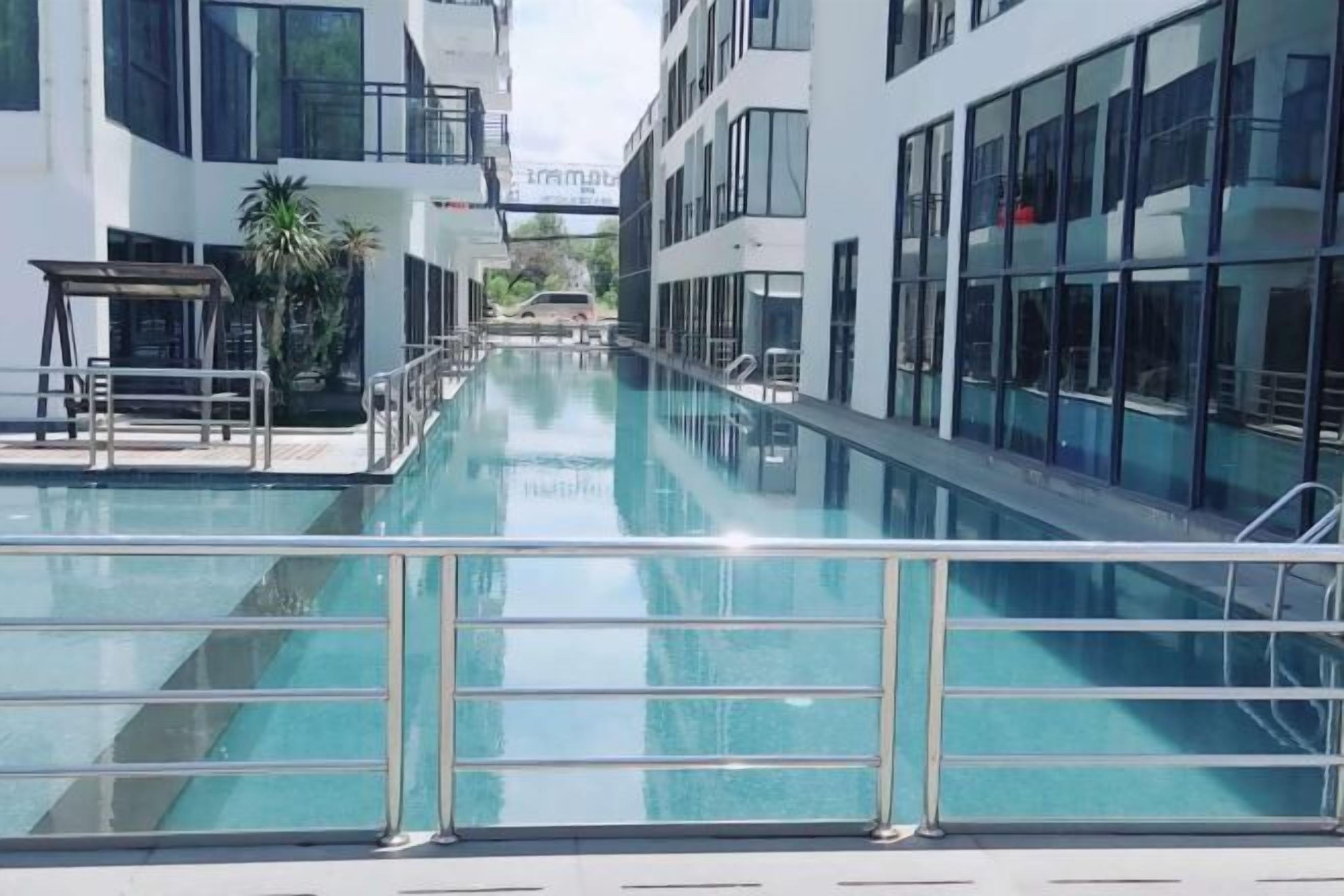 A modern building with a swimming pool, large windows, and a clear sky.