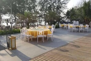 An outdoor dining area with round tables and chairs, surrounded by greenery. - 520 Seaview Hotel (Sihanoukville)