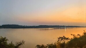 Un lac paisible au coucher du soleil, avec une rive lointaine et un pont.