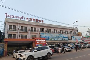 A building with multiple floors, a signboard, and several parked cars.