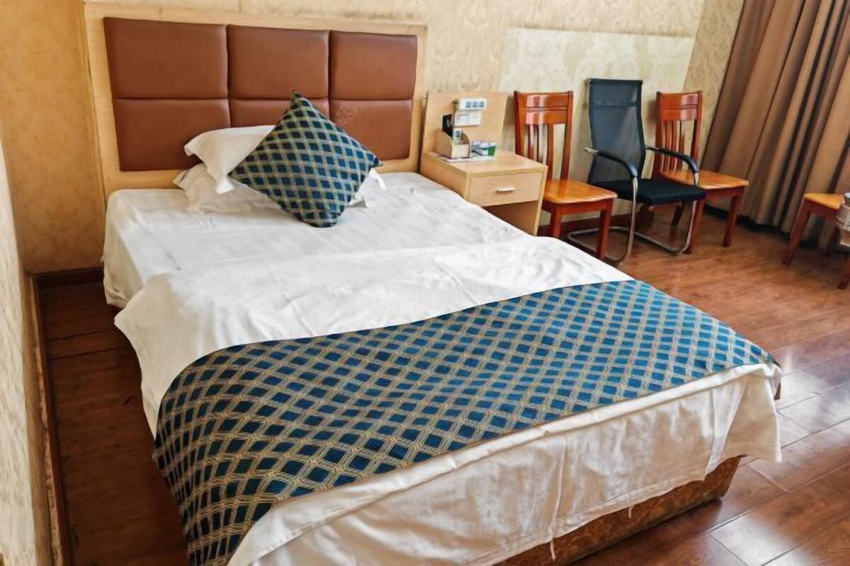 Una habitación de hotel con una cama, un escritorio, dos sillas y una ventana con cortinas.