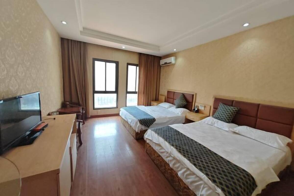 Una habitación de hotel con dos camas, televisión, escritorio y ventana.